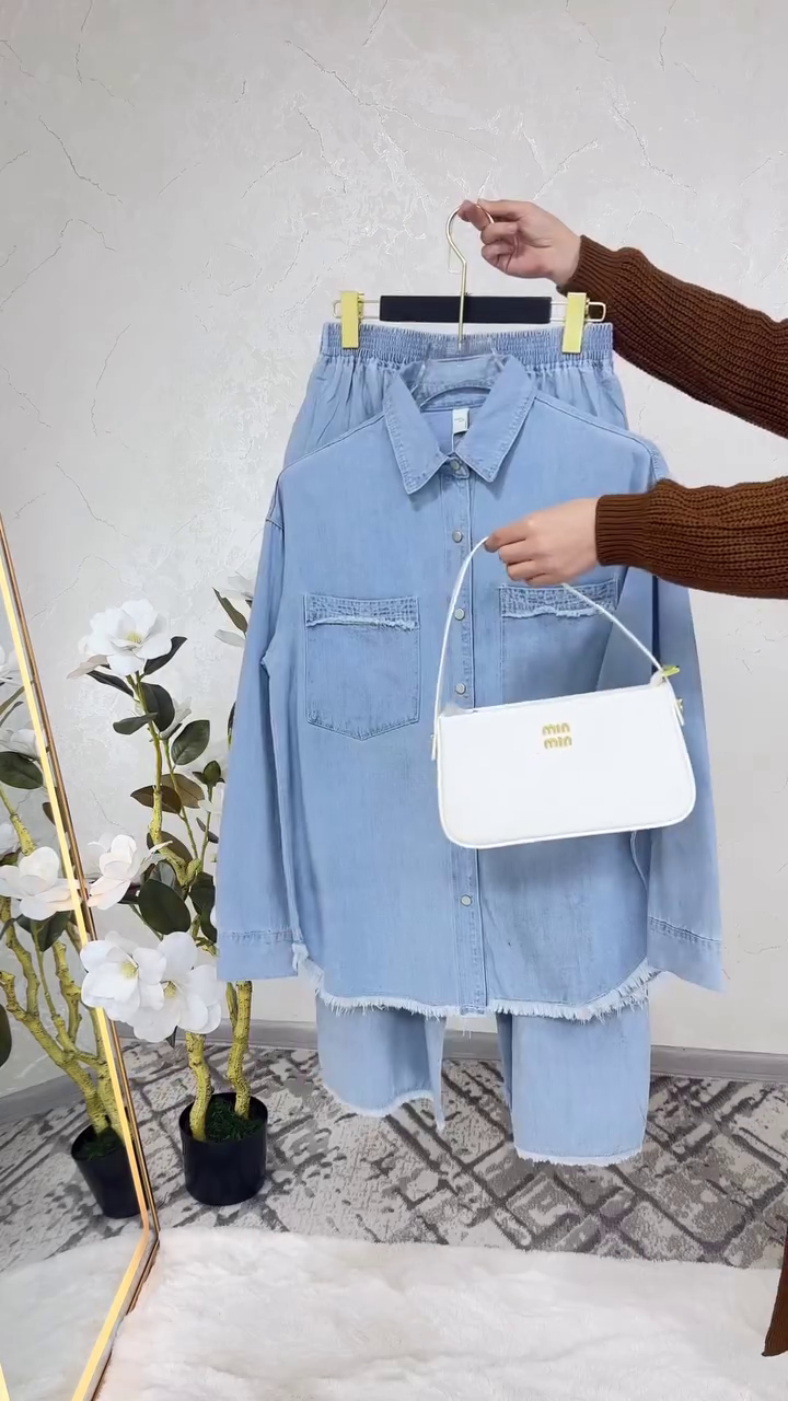 “Denim Details: Chic Frayed Shirt and Coordinating Trousers with a White Handbag”