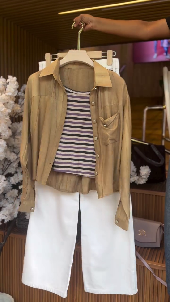 “Layered Chic: Button-Up Shirt over a Striped Tank with White Trousers”
